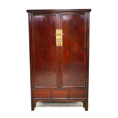 542 - A modern Chinese wooden cabinet, with brass lock, twin panelled doors enclosing shelves and two draw... 