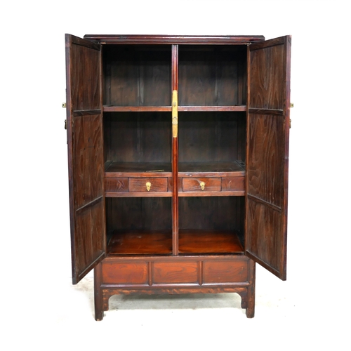 542 - A modern Chinese wooden cabinet, with brass lock, twin panelled doors enclosing shelves and two draw... 