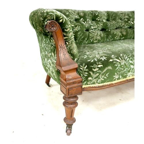 543 - A Victorian two seater settee, with floral carved scroll arms, upholstered in green and cream foliat... 