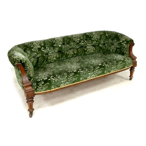 543 - A Victorian two seater settee, with floral carved scroll arms, upholstered in green and cream foliat... 