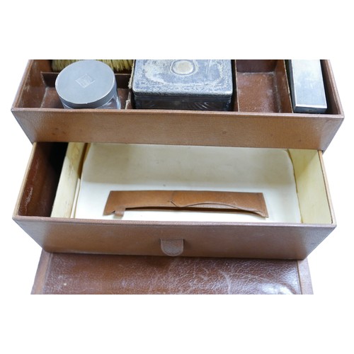 319 - A 1930's pigskin leather travel box with six silver top bottles, a mirror and two brushes hallmarked... 