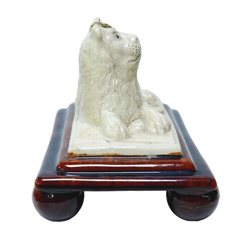 96 - An 18th century Staffordshire spill vase with recumbent lion, treacle glazed base raised upon four b... 