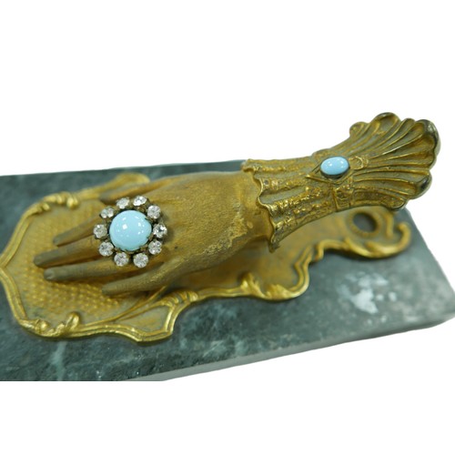 167 - A Victorian letter holder of hand form, adorned with turquoise and paste stones, mounted upon a marb... 