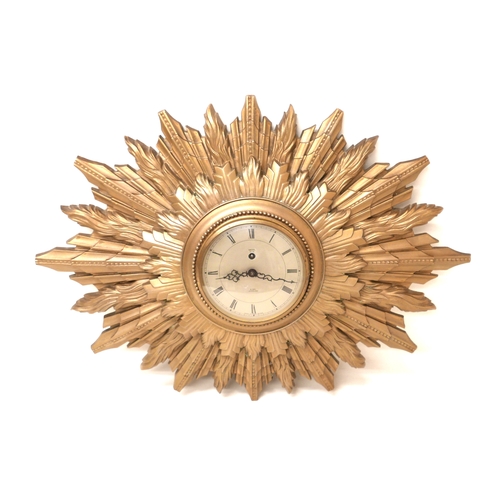 219 - A vintage Smiths sunburst clock, circular dial with black Roman numerals, 8 day movement, cast resin... 