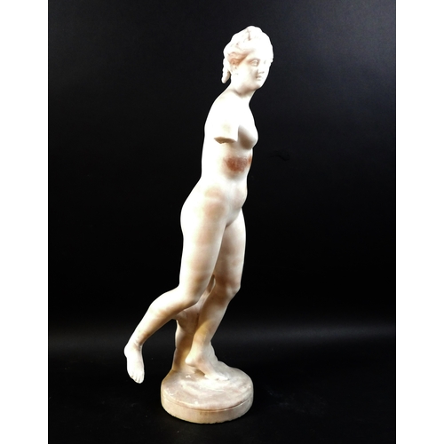 128 - A white marble statue, modelled as a Greek or Roman Goddess, standing nude on her left foot, 15 by 2... 