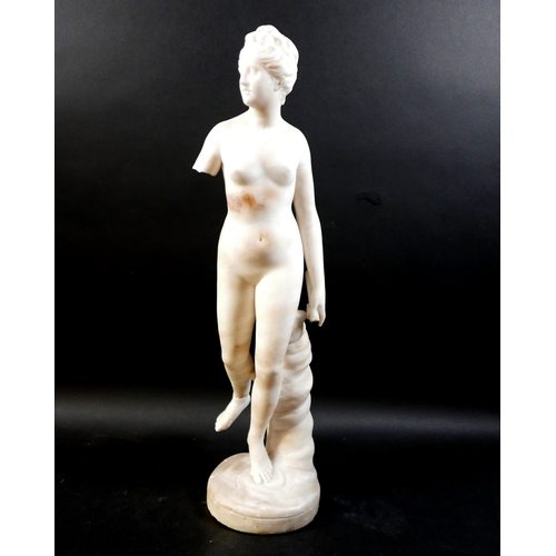 128 - A white marble statue, modelled as a Greek or Roman Goddess, standing nude on her left foot, 15 by 2... 