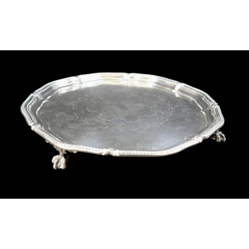 7 - A George V silver tray, with decorative scalloped edge, engraved centre, raised on three ball and cl... 