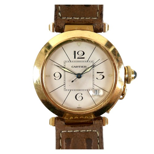 A Cartier Pasha automatic 18ct gold cased wristwatch, circular white dial with 3.6.9.12 Arabic numerals divided by eight lines, surrounding a square minute track and signature, luminous pointed hands, centre seconds, date aperture at 4 o'clock with magnifier to crystal, screw crown attached on a link, set with a cabochon sapphire, stamped to caseback 'Pasha de Cartier Automatic Water Resistant 260ft Swiss Made 18K 1991 M104502', on a brown leather strap, dial 28mm, case 38mm, 44mm across crown, 88.2g gross.