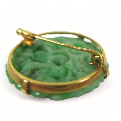 193 - A carved green jade brooch in an Egyptian yellow gold 625 setting, 3cm diameter, 8.7 grams.