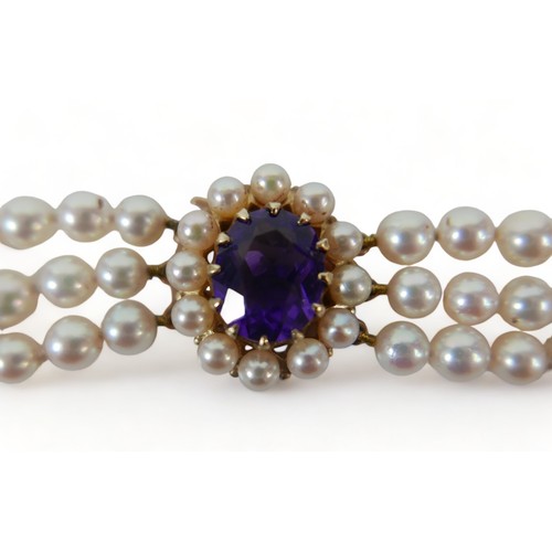 337 - A good quality triple string of pearls with a hallmarked amethyst set yellow gold clasp, 38cm long, ... 