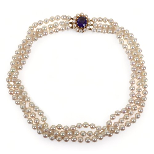 337 - A good quality triple string of pearls with a hallmarked amethyst set yellow gold clasp, 38cm long, ... 