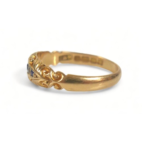 300 - An 18ct yellow gold ring, set with three blue sapphires, central 2.5mm, and two small diamonds withi... 