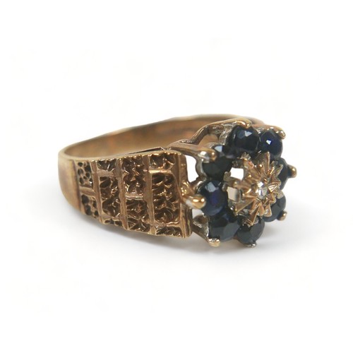 274 - A 9ct gold ring, set with a flowerhead of dark bue sapphires around a single small diamond, with tex... 