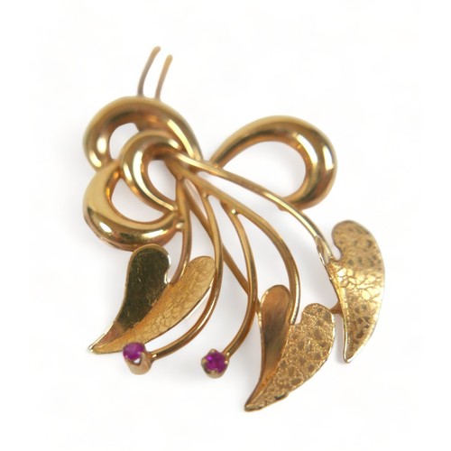 277 - An 18ct gold and ruby brooch, set with two rubies, shaped as three heart shaped textured leaves in a... 