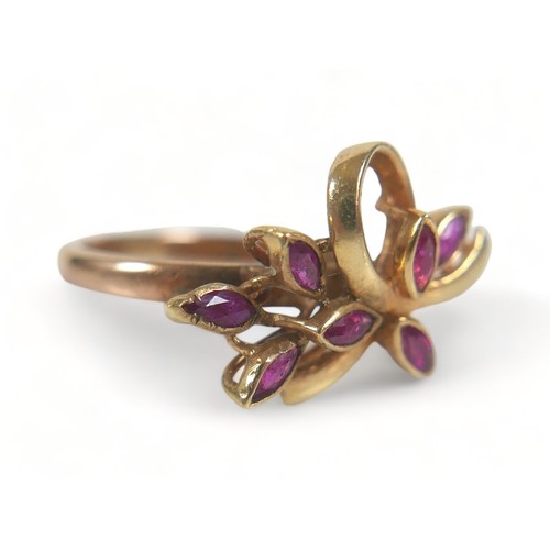 223 - A 9ct gold and ruby dress ring, with seven marquise-cut rubies,  set in a left style with bow, band ... 