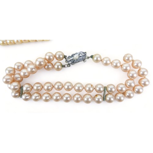 310 - A two-strand set of graduated pearls, the clasp set with a single diamond, the pearls ranging in siz... 