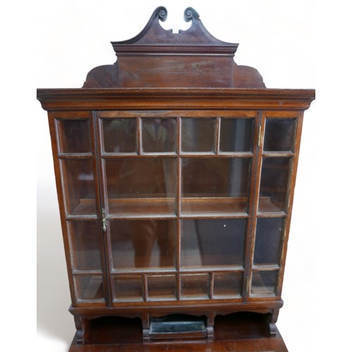 634 - An early 1900s mahogany davenport bookcase with a glazed bookcase top above a leather inset slope an... 