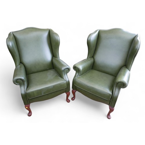 633 - A pair of Paul Sorren green leather wing back library chairs, 78 by 87 by 110cm.