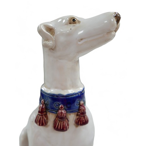 81 - A pair of pottery sculptures, modelled as white greyhounds, wearing blue collars with red tassels, o... 