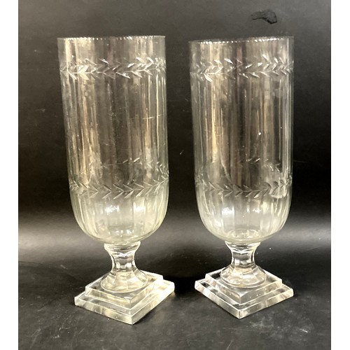 108 - A pair of Victorian tall, clear glass vases, wheel engraved with leaf rim, raised on a column and sq... 