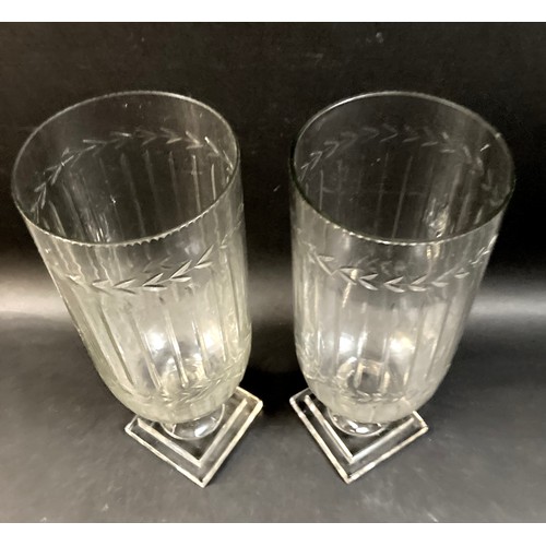 108 - A pair of Victorian tall, clear glass vases, wheel engraved with leaf rim, raised on a column and sq... 