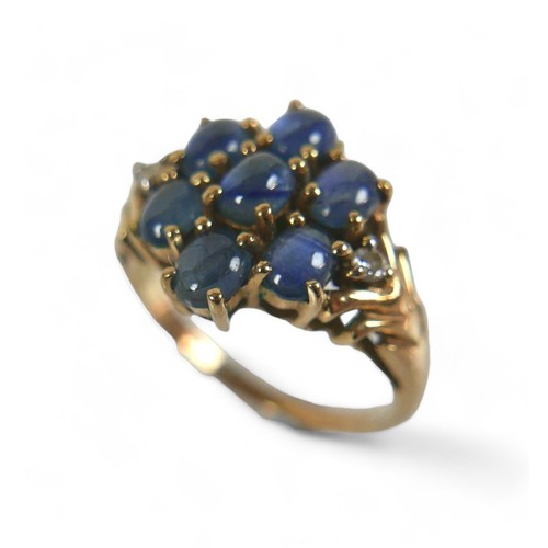 70 - A 9ct gold, diamond and blue cabochon stone ring, a central flowerhead of seven blue stones, with a ... 