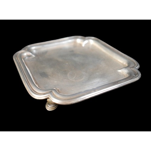 7 - A George I silver tray, of square form with incuse corners and reeded rim, raised on four hoof feet,... 