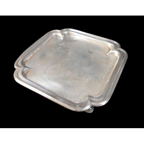 7 - A George I silver tray, of square form with incuse corners and reeded rim, raised on four hoof feet,... 