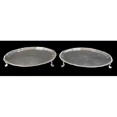 3 - A pair of George III silver salver trays, with scalloped rim and gadrooned edge, raised on three hoo... 