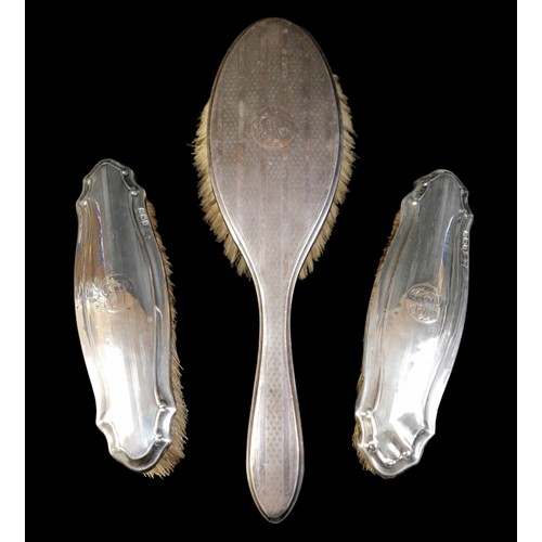 22 - A group of silver-backed dressing table items, comprising a hand mirror, two brushes with repousse d... 