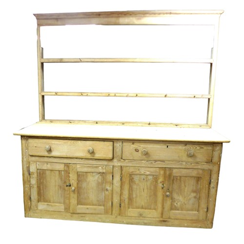 569 - A Victorian stripped pine dresser, with two drawers over cupboards, and open plate rack section abov... 