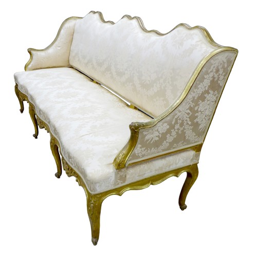 572 - A 19th century giltwood settee, three seater, with floral carved frame, upholstered in cream damask ... 