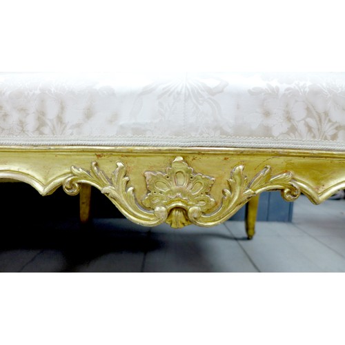 572 - A 19th century giltwood settee, three seater, with floral carved frame, upholstered in cream damask ... 