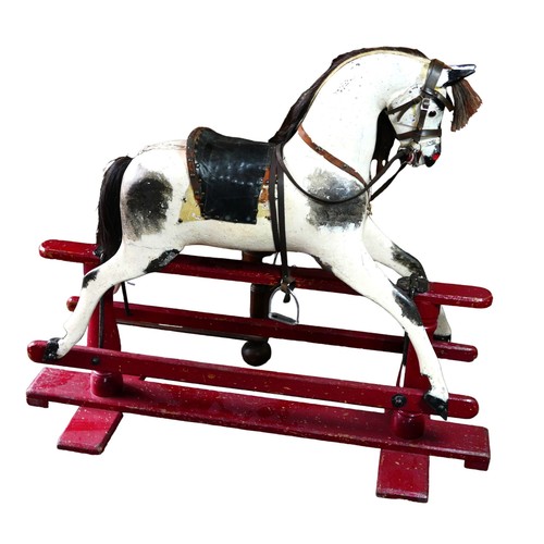 334 - A Victorian hand painted rocking horse, piebald pattern, with saddle and reins, upon a red trestle b... 