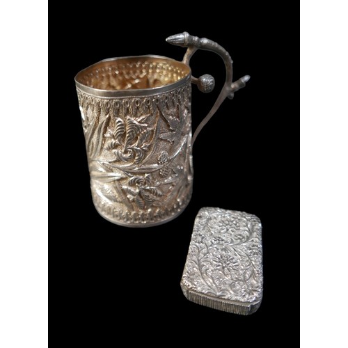 24 - A eastern white metal tankard and a vesta case, both with foliate decoration, tankard 11 by 6.5 by 1... 