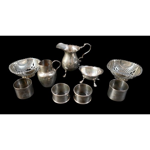 31 - A collection of silver items, comprising two jugs, four napkin rings, a salt and a pair of silver sw... 