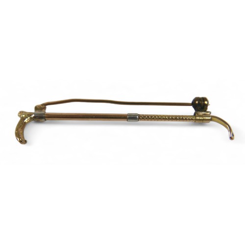 124 - Three gold brooches, comprising a platinum 15ct yellow gold riding crop, 6cm long, a diamond horsesh... 