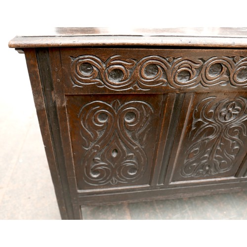 533 - An 18th century carved oak coffer, two plank top with loop hinges, three panel front with scrolling ... 