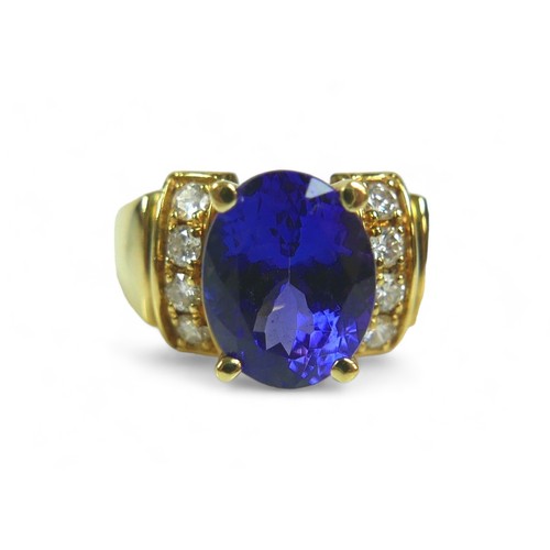 141 - A tanzanite, diamond and 18k gold ring, the large blue oval cut central tanzanite flanked by eight b... 