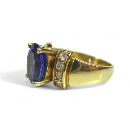 141 - A tanzanite, diamond and 18k gold ring, the large blue oval cut central tanzanite flanked by eight b... 