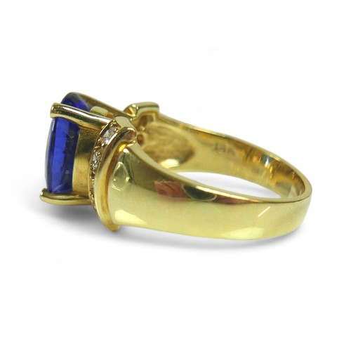 141 - A tanzanite, diamond and 18k gold ring, the large blue oval cut central tanzanite flanked by eight b... 