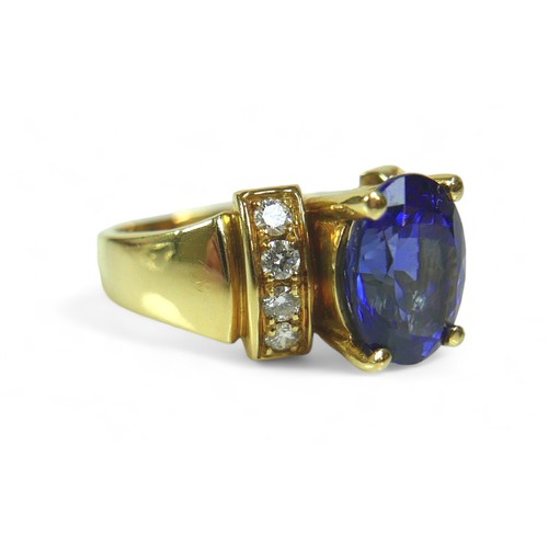 141 - A tanzanite, diamond and 18k gold ring, the large blue oval cut central tanzanite flanked by eight b... 