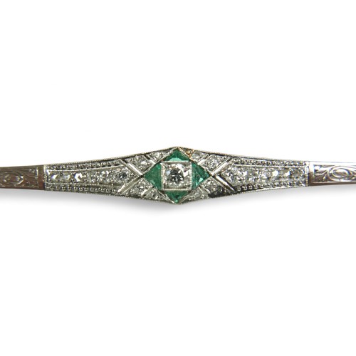 148 - An Art Deco diamond and emerald bar brooch, on 18ct gold and platinum setting, the central round cut... 