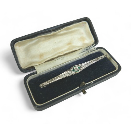 148 - An Art Deco diamond and emerald bar brooch, on 18ct gold and platinum setting, the central round cut... 