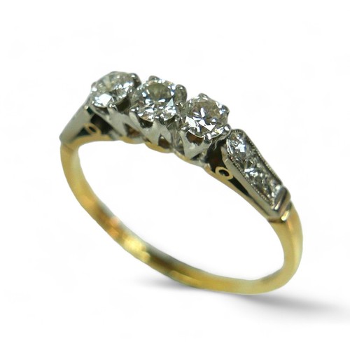 136 - An 18ct gold three stone diamond ring, with additional small diamonds to the shoulders, size U, the ... 