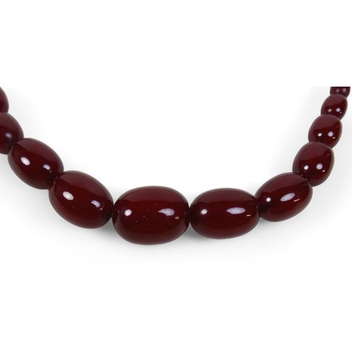 119 - A cherry amber bead necklace, of sixty graduating beads, largest bead 21.8 by 29mm, with screw clasp... 