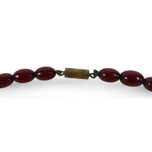 119 - A cherry amber bead necklace, of sixty graduating beads, largest bead 21.8 by 29mm, with screw clasp... 