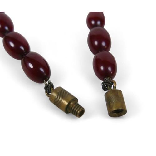 119 - A cherry amber bead necklace, of sixty graduating beads, largest bead 21.8 by 29mm, with screw clasp... 