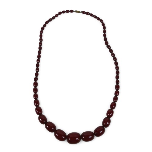 119 - A cherry amber bead necklace, of sixty graduating beads, largest bead 21.8 by 29mm, with screw clasp... 