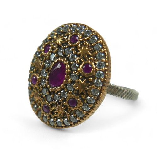 80 - A ruby and white stone ring, the oval and round-cut rubies alternating with rings of clear stones an... 